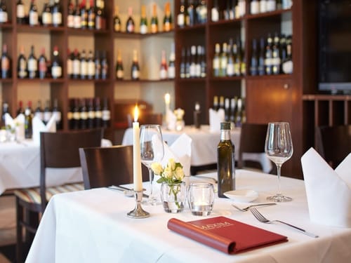eingedeckter Tisch mit weißer Tischdecke und Serviette, Wein-, Wassergläser und Deko