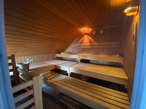 Innenansicht einer gemütlichen Sauna mit Holzbänken und dezenter Beleuchtung.