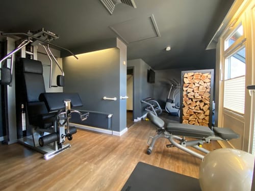 Moderner Fitnessraum mit Trainingsgeräten, Holzdekor und natürlichem Licht