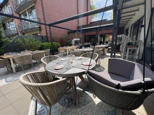 Gemütlicher Außenbereich eines Restaurants mit modernen Sitzmöbeln und überdachter Terrasse.