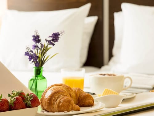 kleines Frühstück am Bett mit Croissant, Erdbeeren, Saft und Kaffee