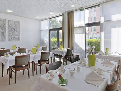 weiß eingedeckte Tische im Frühstücksraum mit Zugang zur Terrasse