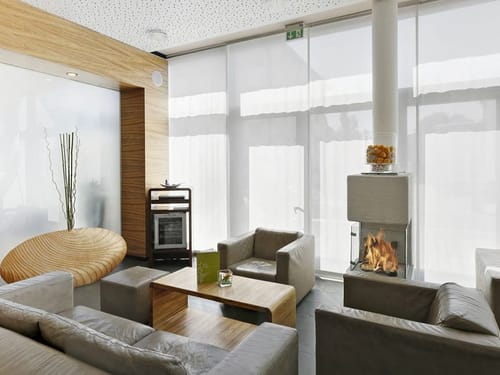 zwei Sessel, Couch, Hocker, Tushc und Kaminfeuer in der Lobby