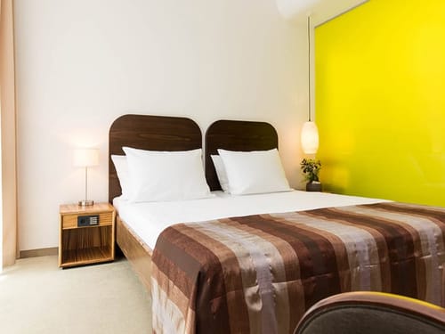 einfaches Doppelzimmer mit Doppelbett und Nachttisch