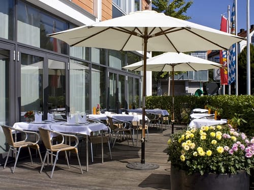 verschieden weiß eingedeckte Tisch auf der Terrasse mit Sonnenschirmen