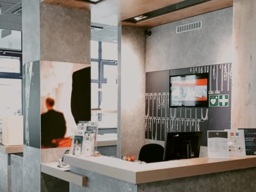 Moderne Hotelrezeption mit Schreibtisch und Bildschirm im Hintergrund
