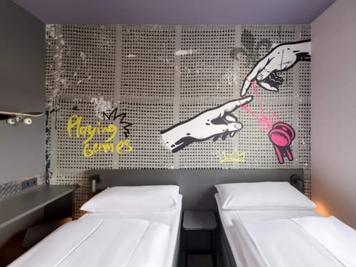 Modernes Hotelzimmer mit künstlerischer Wandgestaltung und zwei Einzelbetten