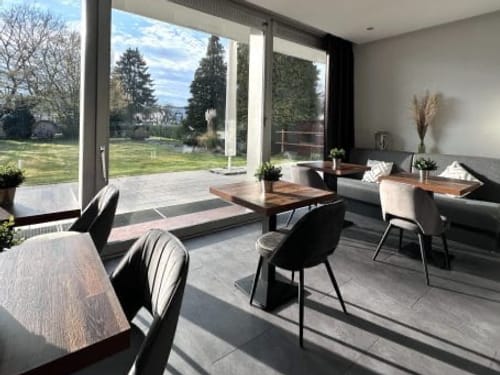 Moderner Frühstücksraum mit Blick auf einen Garten durch große Fenster