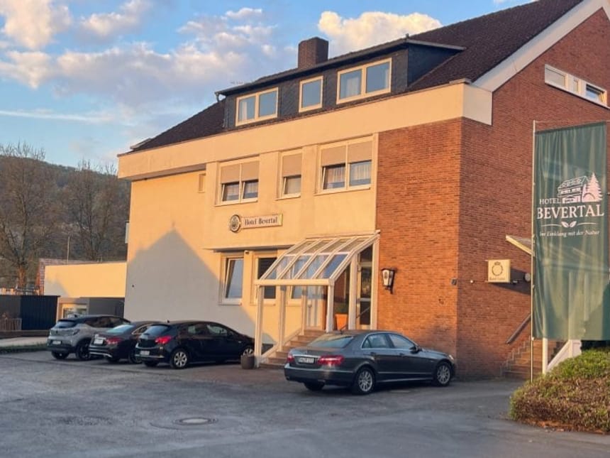 Außenansicht des Hotel Bevertal mit Parkplatz und Banner
