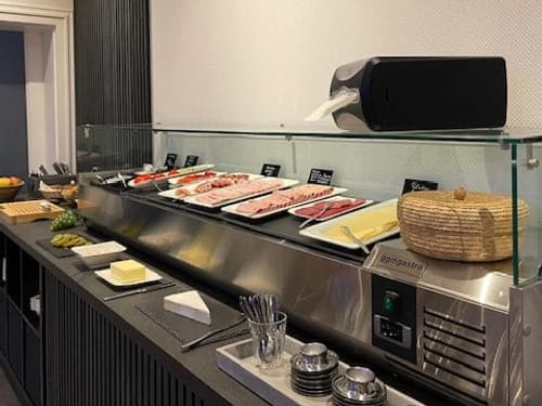 Frühstücksbuffet mit verschiedenen Aufschnittarten, Butter und Getränken