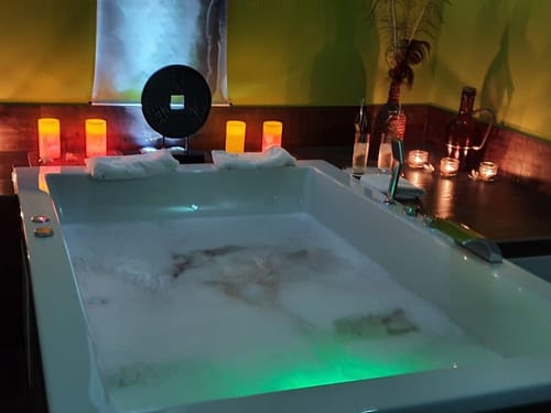 Wellnessbereich mit Badewanne und Kerzen am Rande