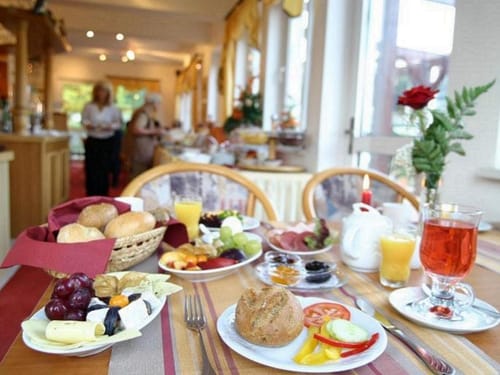 gedeckter Frühstückstisch mit einer großen Auswahl an Wurst, Käse, Rohkost, Obst, Brötchen, Kaffee und Saft