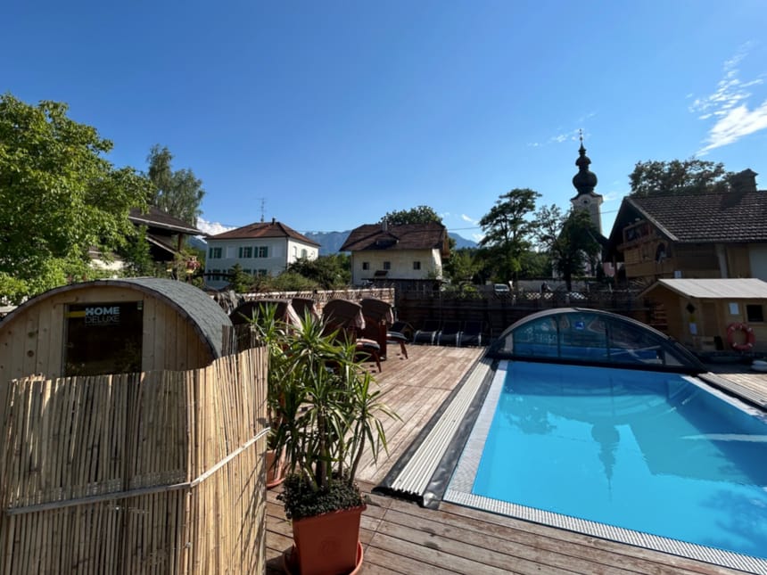 Außenbereich mit Sauna, Pool und Blick auf eine Kirche in einer malerischen Umgebung.