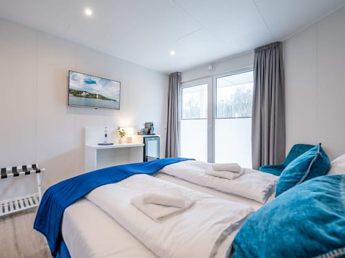 Doppelzimmer Standard mit Boxspringbett, Sessel, Sideboard und TV