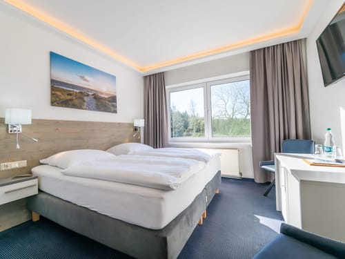 Helles Zimmer mit TV, Schreibtisch und zwei Stühlen