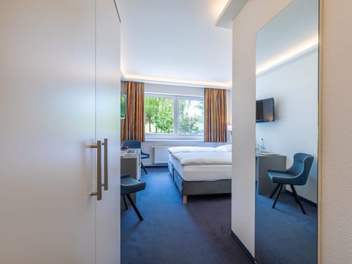 Bett, Schrank, TV, Schreibtisch und zwei Stühle