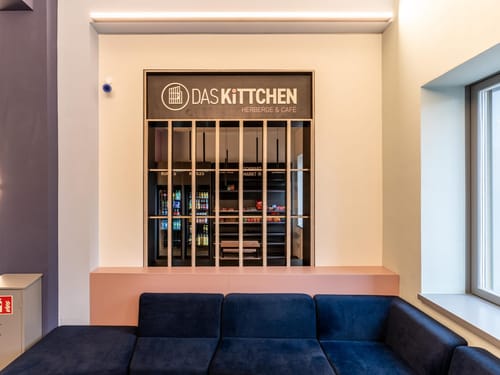 Lounge-Bereich im Das Kittchen Herberge & Café mit blauem Sofa und integriertem Snack-Markt