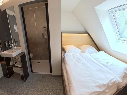 Kleines Zimmer mit einer Dusche, Waschbecken und einem Dachfenster