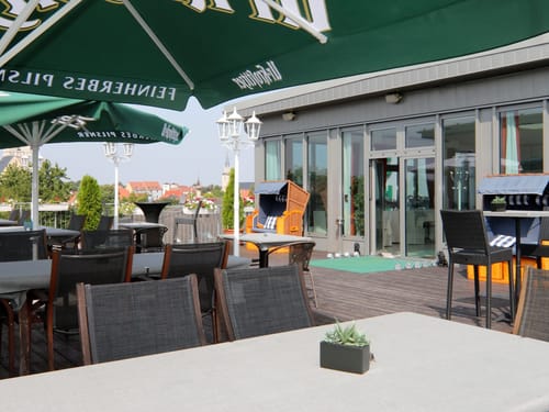 Stilvolle Dachterrasse mit Strandkorb und Stadtpanorama – perfekt für entspannte Stunden in der Außengastronomie