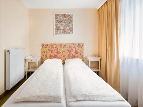 Doppelzimmer mit floralem Kopfteil, weißer Bettwäsche und gemütlicher Atmosphäre in einem Hotel