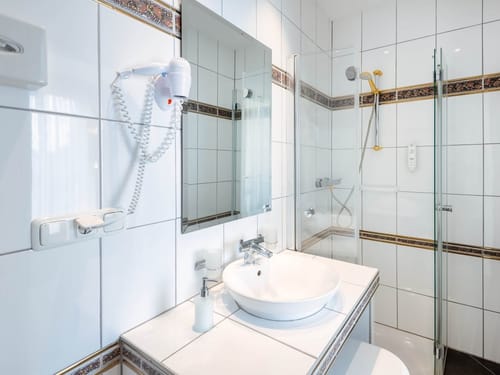 Helles und sauberes Hotelbadezimmer mit Glasduschkabine, elegantem Aufsatzwaschbecken und hochwertiger Ausstattung für anspruchsvolle Gäste