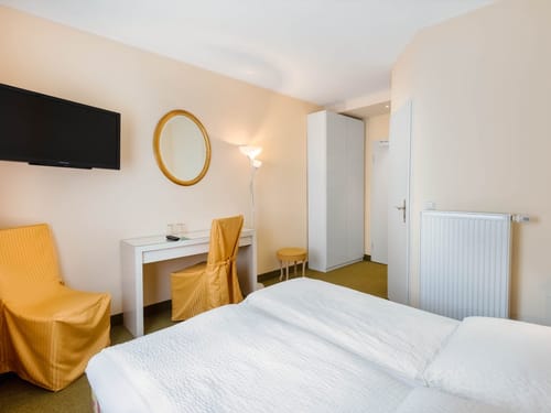 Komfortables Hotelzimmer mit Doppelbett, Schreibtisch und stilvollen goldenen Akzenten für einen angenehmen Aufenthalt