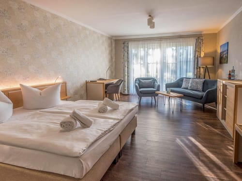 geräumiges Doppelzimmer mit Doppelbett, Couch, Sessel, Tisch und Schreibtisch