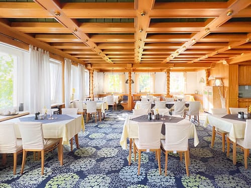 Gemütliches Restaurant mit Holzelementen und hellen Tischdecken