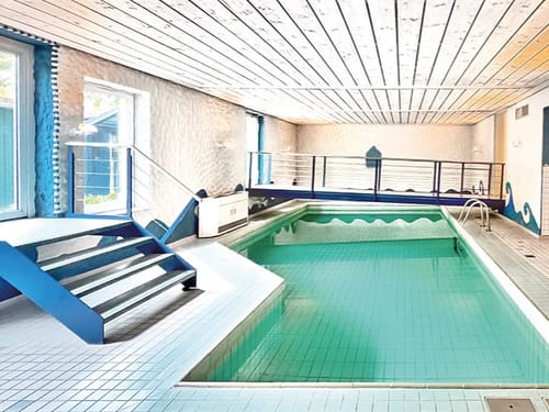 Moderner Innenpool mit Treppe und Geländer in elegantem Design.