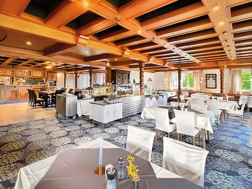 Elegantes Restaurantinterieur mit Holzbalkendecke und gedeckten Tischen