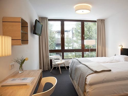 Boxspringbett, Schreibtisch, Stuhl, TV und Panoramafenster im Komfortzimmer