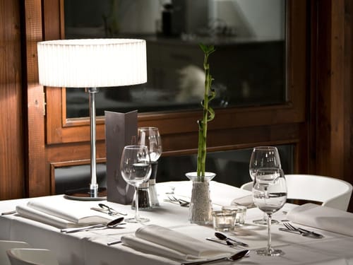 Hotelrestaurant mit weiß eingedeckten Tischen und Stehlampe auf dem Tisch