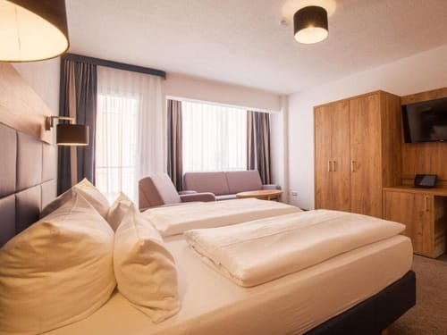 Modernes Hotelzimmer mit Doppelbett, Holzmöbeln und Sofa.