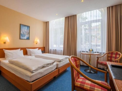 Gemütliches Hotelzimmer mit zwei Einzelbetten, einem Tisch und Sesseln