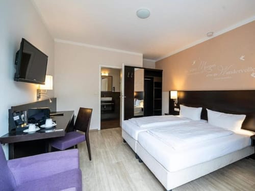 Modernes Hotelzimmer mit Doppelbett und Schreibtisch.