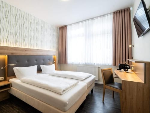 Modern eingerichtetes Hotelzimmer mit Doppelbett und Schreibtisch.