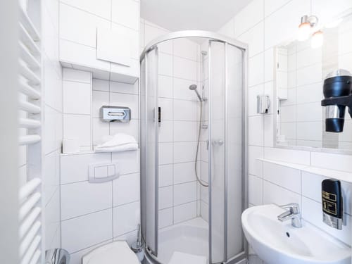 Modernes Badezimmer mit Duschkabine und weißen Fliesen.