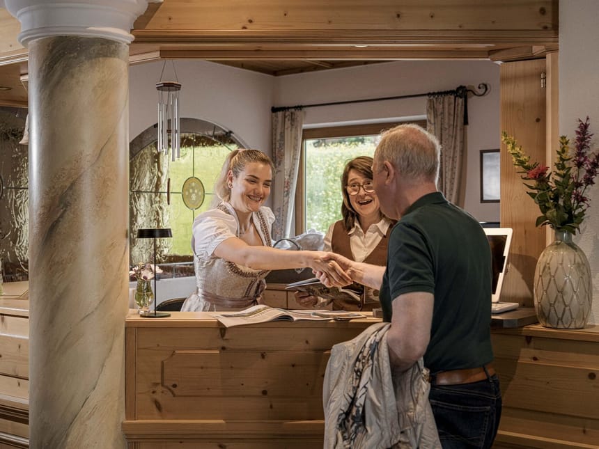 Freundliche Begrüßung an der Rezeption eines Hotels im alpinen Stil
