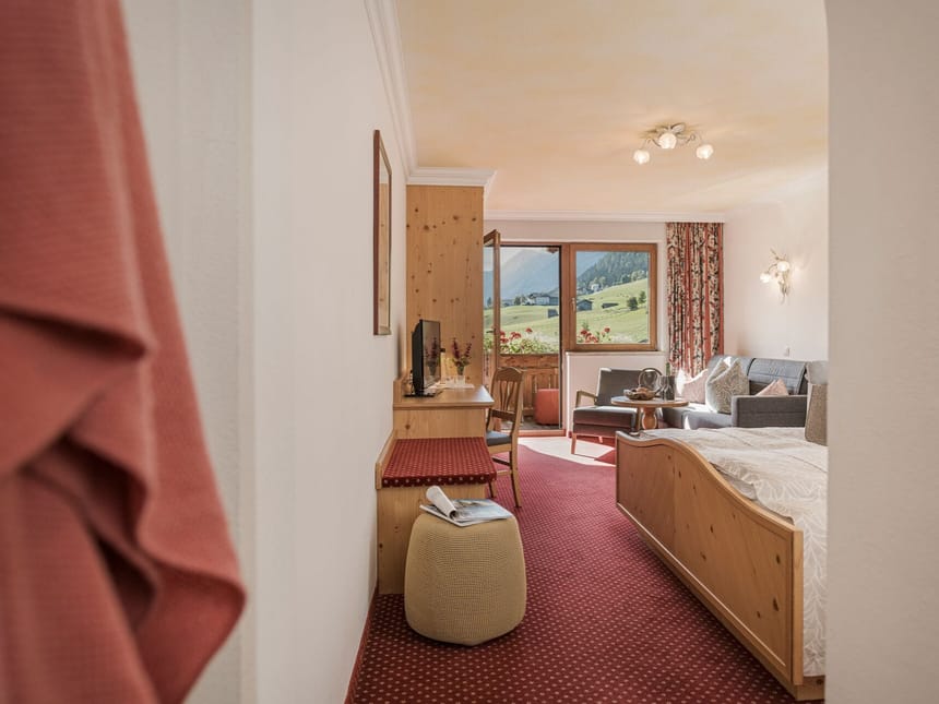 Gemütliches Hotelzimmer mit Holzmöbeln und Blick auf die Berge