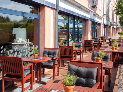 Terrasse mit eingedeckten Tischen und Stühlen