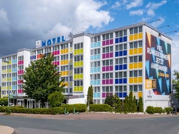 Buntes Hotelgebäude mit modernem Design und großem Werbeposter an der Seite.