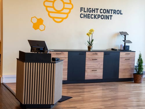 Empfangsbereich mit Schreibtisch, Blumen und "Flight Control Checkpoint" an der Wand.