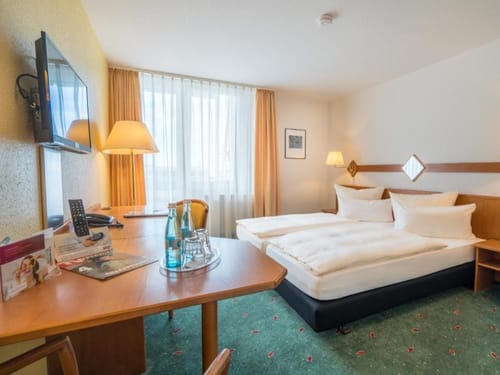 Komfortables Hotelzimmer mit Doppelbett, Schreibtisch und Flachbildfernseher.
