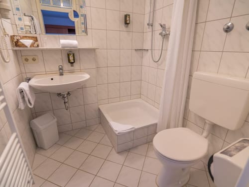 Modernes, gefliestes Badezimmer mit Dusche, Waschbecken und WC