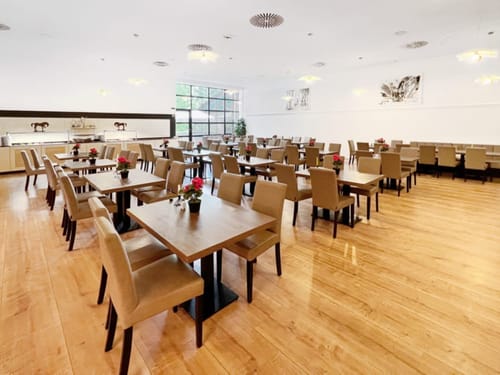 Großer, heller Saal mit Tischen und Stühlen