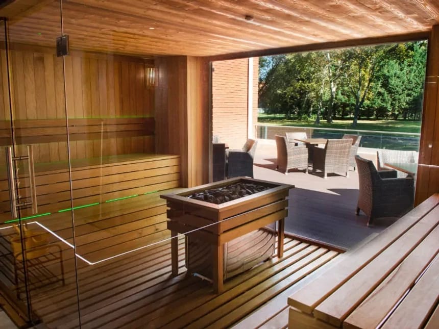 Moderne Sauna mit Glasfront und Blick auf eine Außenterrasse.
