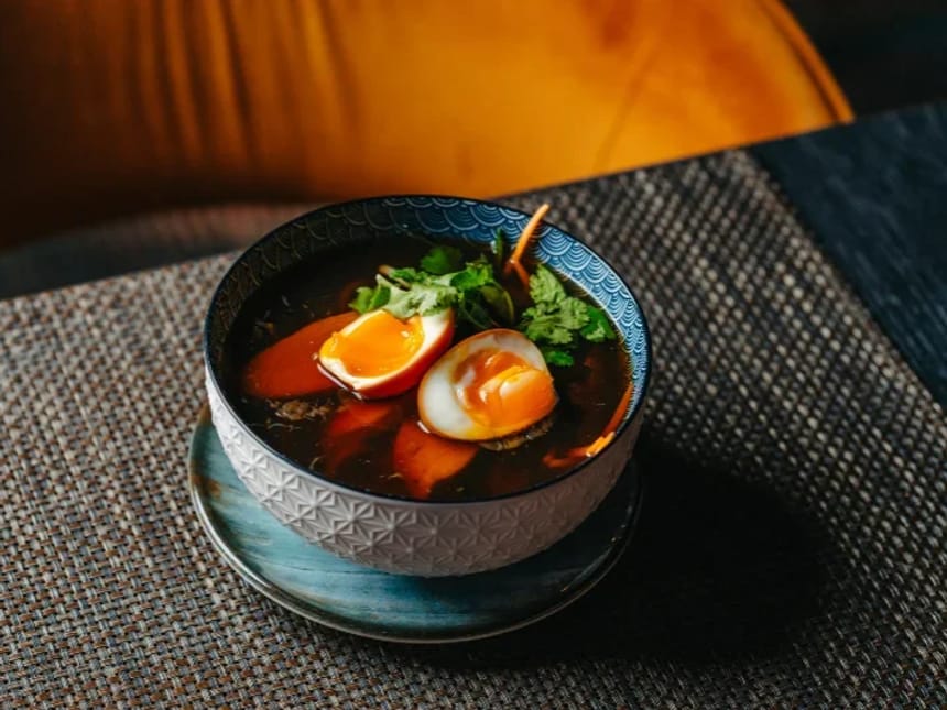 Schüssel mit Ramen-Suppe, verziert mit weichen Eiern und Koriander