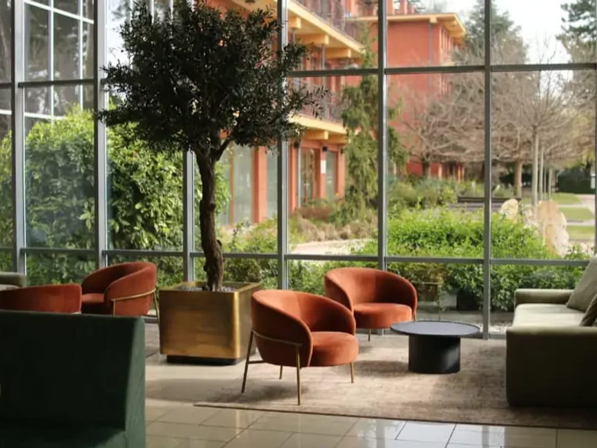 Eleganter Loungebereich mit modernen Sesseln und großem Fenster mit Gartenausblick.