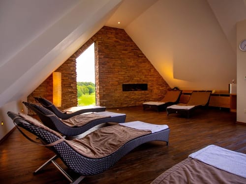 Entspannungsraum mit Liegen und Kamin in einem modernen Wellnessbereich