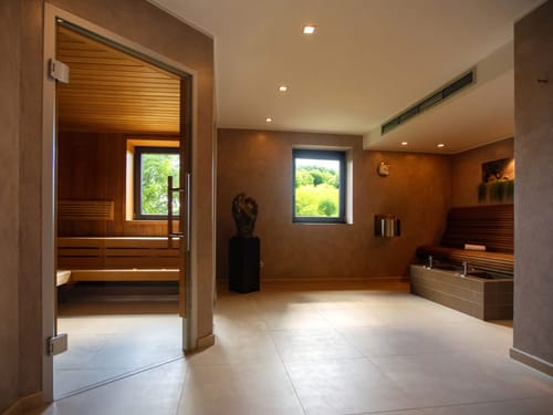 Moderner Sauna- und Wellnessbereich mit Holz-Ausstattung und Blick ins Gruene.